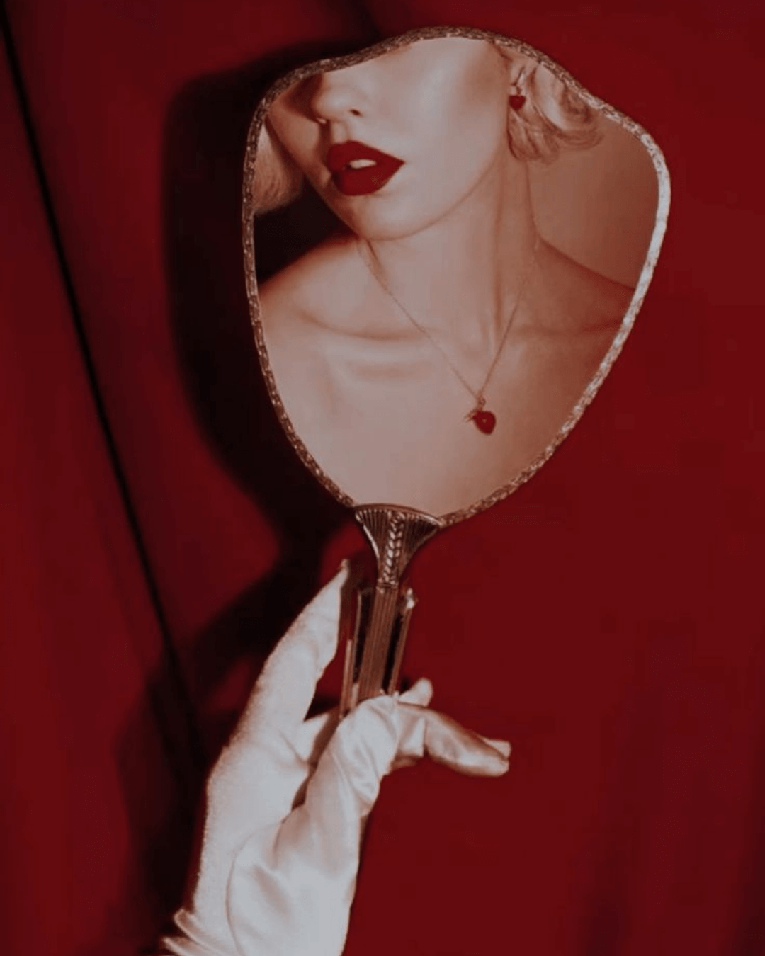 Brand reflection concept in red tones Woman holding a vintage mirror reflecting her face against a red background