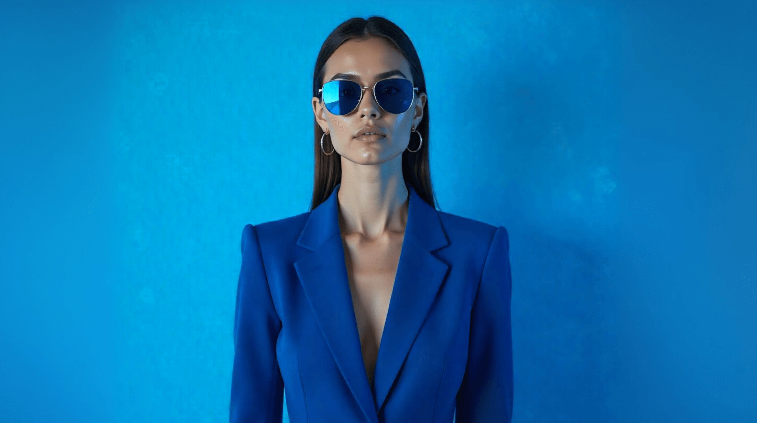 Woman in bold blue blazer and sunglasses against a blue background