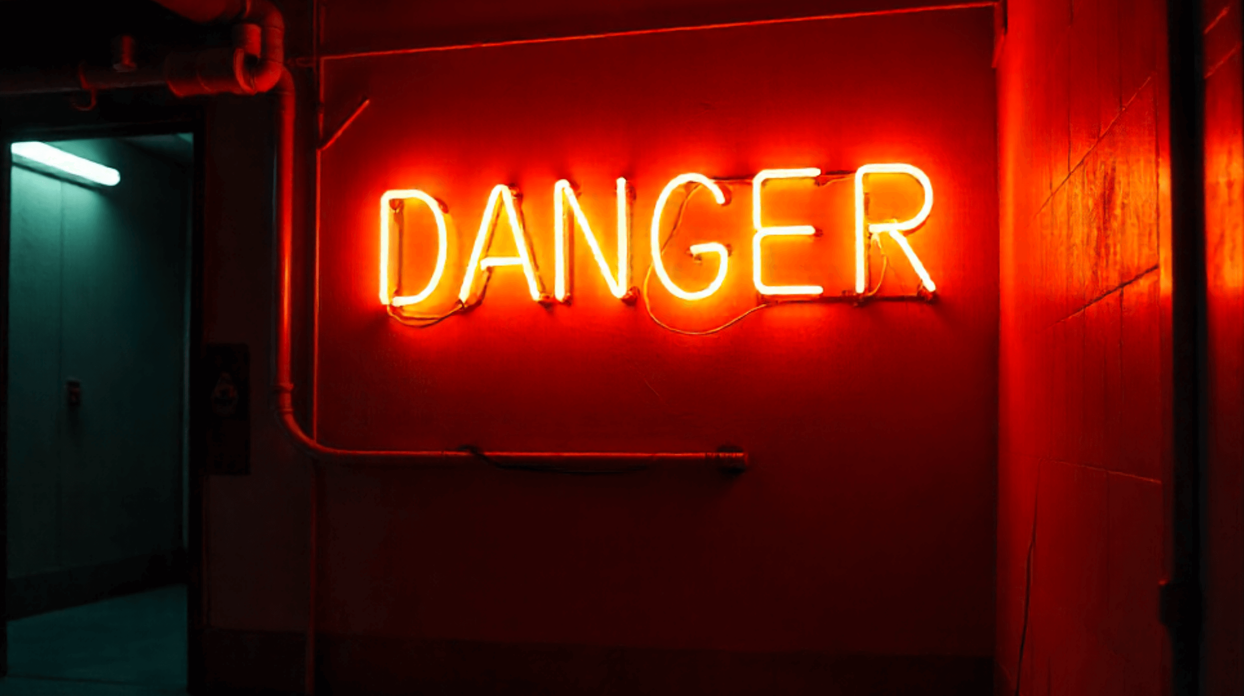Neon sign glowing with the word danger in bright orange red light